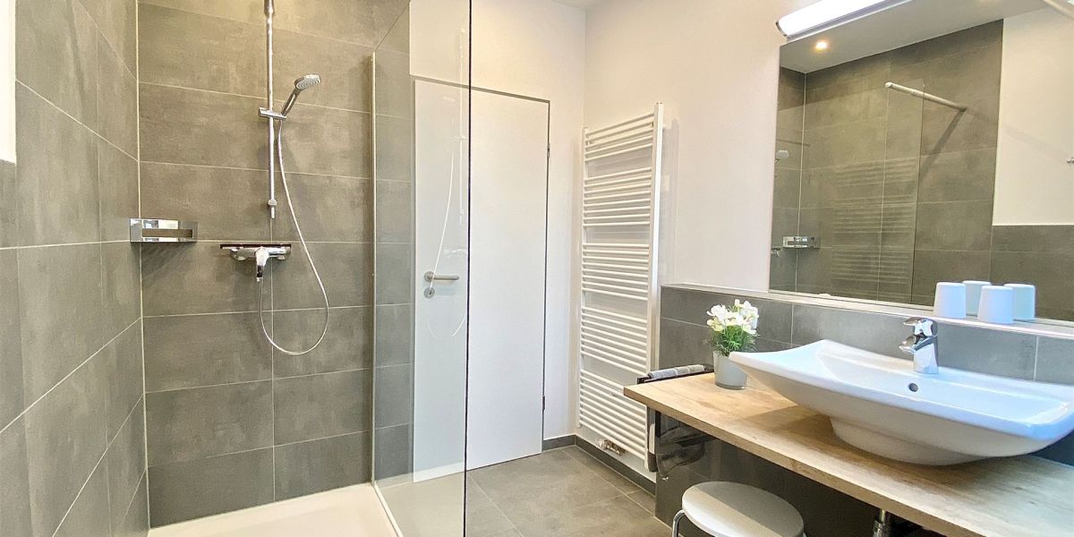 Modernes Badezimmer mit Dusche, Waschkonsole und guter Beleuchtung im Apartment W5