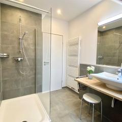 Modernes Badezimmer mit Dusche, Waschkonsole und guter Beleuchtung im Apartment W5