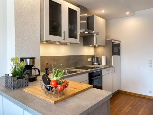 Küchentresen mit großzügigem Arbeitsbereich: Die Komfort-Küche im Apartment W6 bietet viel Platz für gemeinsames Kochen im Urlaub 