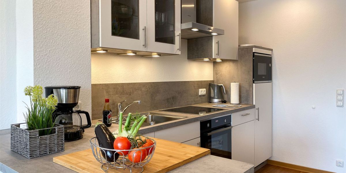 Küchentresen mit großzügigem Arbeitsbereich: Die Komfort-Küche im Apartment W6 bietet viel Platz für gemeinsames Kochen im Urlaub 
