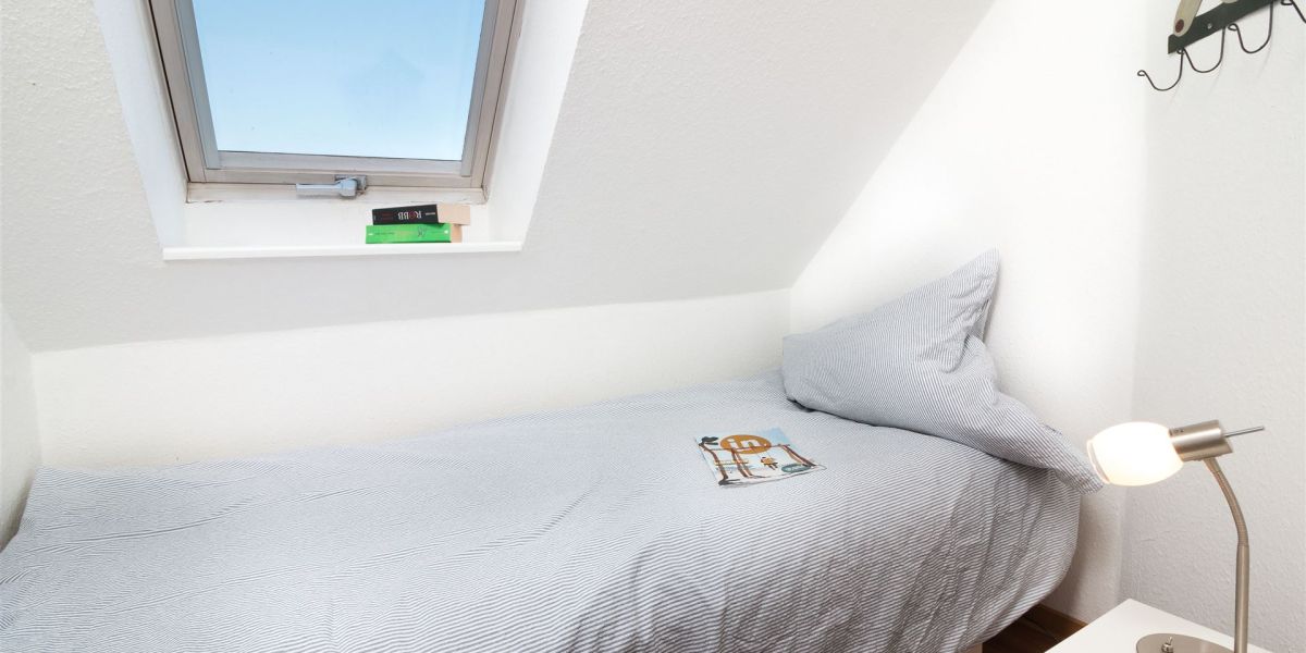 Kleines, helles Gäste- oder Kinderschlafzimmer mit Einzelbett, Garderobe und Leselampe