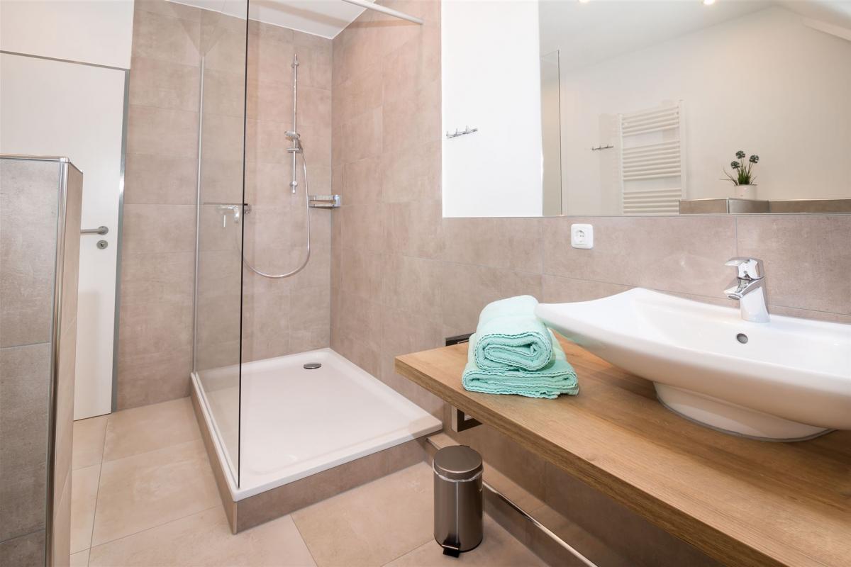 Waschtisch auf Holzkonsole und große offene Dusche mit Glas-Seitenwand im Komfort-Apartment W7
