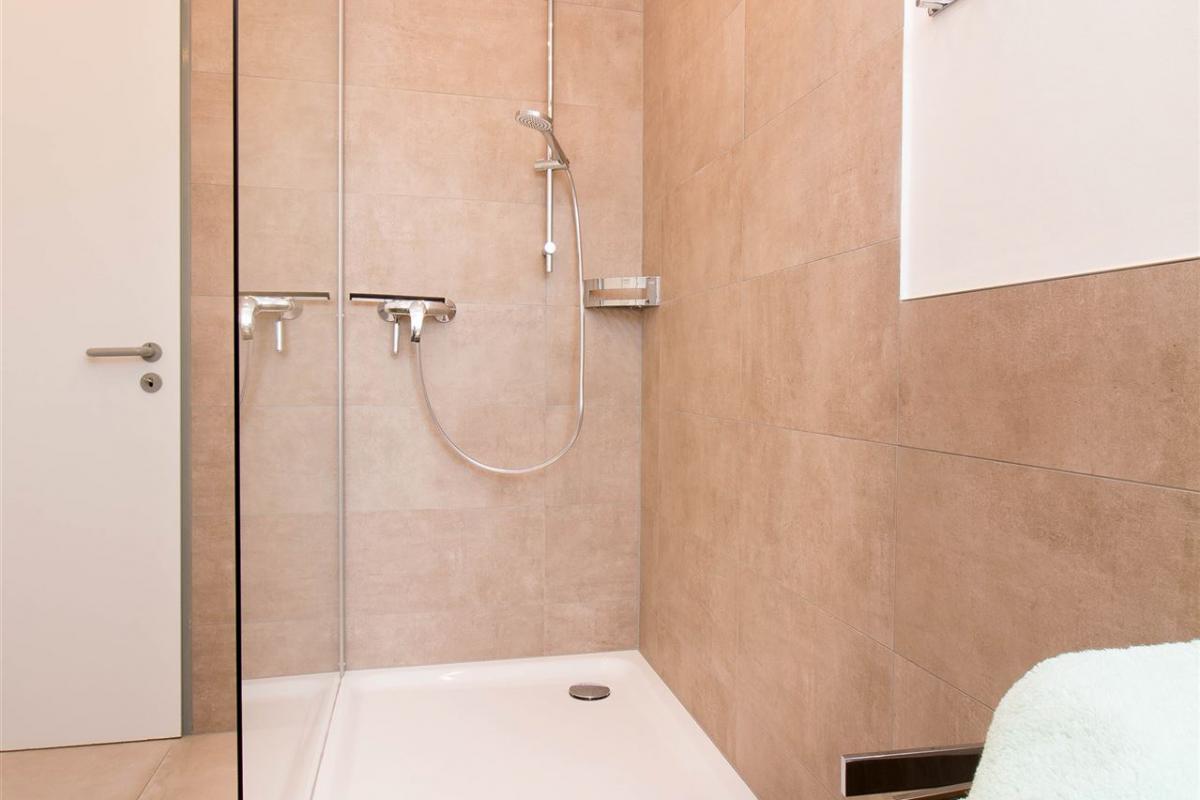 Große offene Dusche mit seitlichem Glaselement im Badezimmer des Dachgeschoss-Apartments W7
