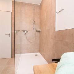 Große offene Dusche mit seitlichem Glaselement im Badezimmer des Dachgeschoss-Apartments W7
