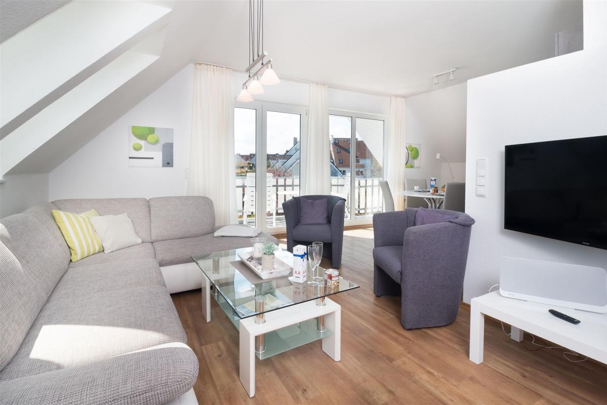Grau-weiße Wohnlandschaft mit Sesseln und Smart-TV im Komfort-Apartment W7