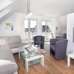 Grau-weiße Wohnlandschaft mit Sesseln und Smart-TV im Komfort-Apartment W7