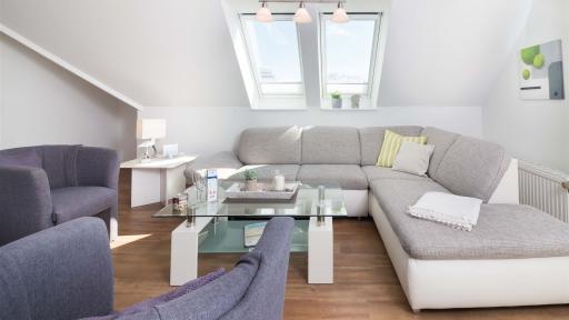 Sitzecke mit Winkel-Couch und Sesseln im Komfort-Apartment W7