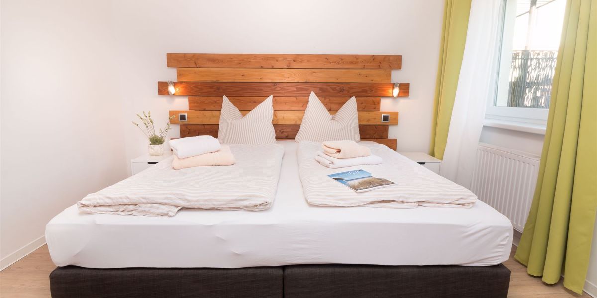 Boxspring-Doppelbett mit modernem Holzpanel im Schlafzimmer des Komfort-Apartments K1