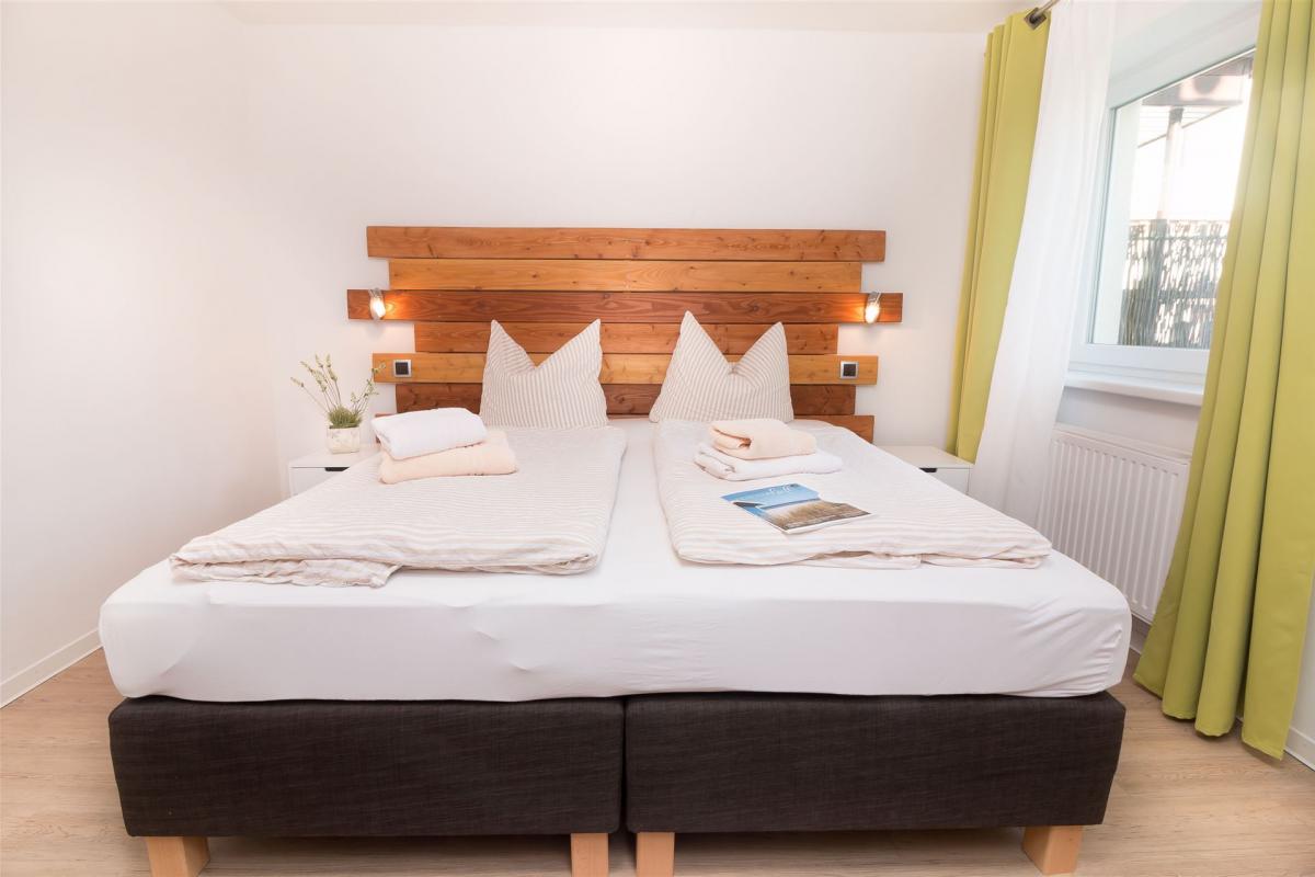 Boxspring-Doppelbett mit modernem Holzpanel im Schlafzimmer des Komfort-Apartments K1