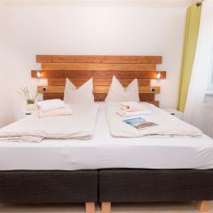 Boxspring-Doppelbett mit modernem Holzpanel im Schlafzimmer des Komfort-Apartments K1