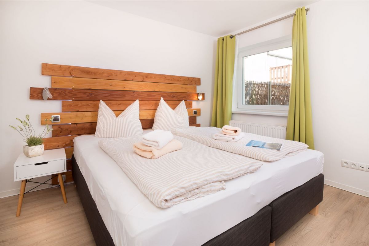 Einladender Schlafraum mit Boxspringbett und Holz-Wandpaneel im Komfort-Apartment K1