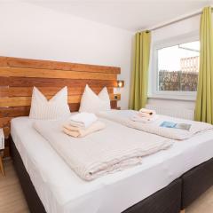 Einladender Schlafraum mit Boxspringbett und Holz-Wandpaneel im Komfort-Apartment K1