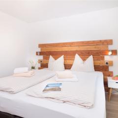 Schlafzimmer mit Doppel-Boxspringbett und moderner Holz-Rückwand im Strandhaus-Apartment K1