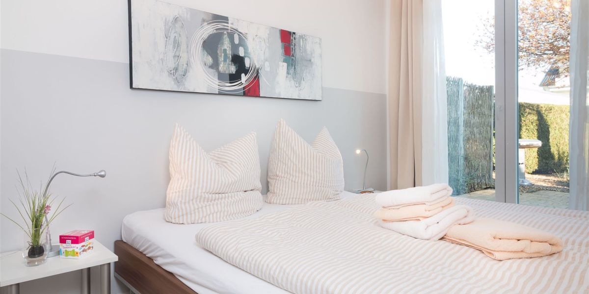 Schlafraum mit Doppelbett und Austritt auf Terrasse des Komfort-Apartments K1