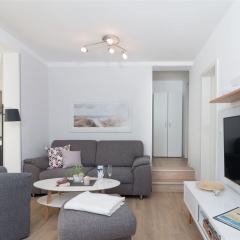 Heller Wohnraum mit Sitzgruppe und Wand-TV (4K/UHD) im Komfort-Apartment K1
