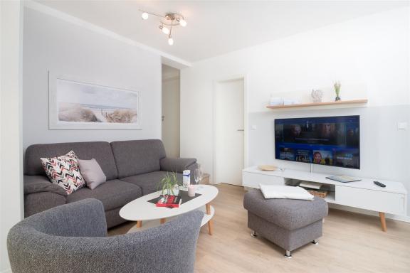 Edel anmutende, in Grau gehaltene Sitzecke mit wandhängendem Smart-TV im Komfort-Apartment K1