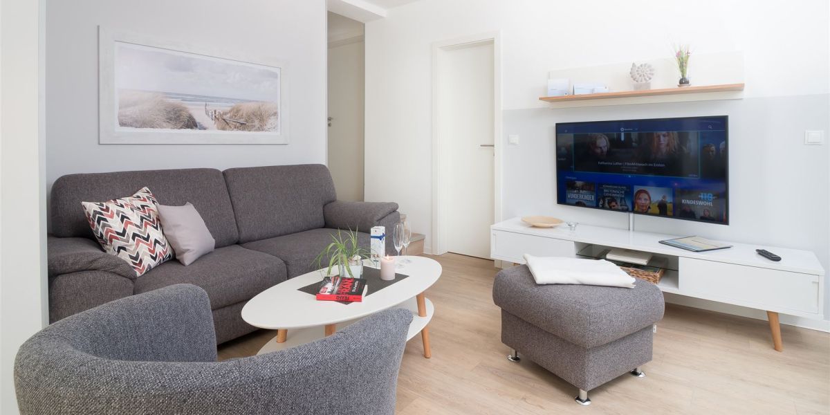 Edel anmutende, in Grau gehaltene Sitzecke mit wandhängendem Smart-TV im Komfort-Apartment K1
