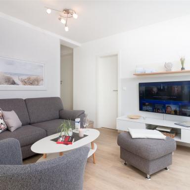Edel anmutende, in Grau gehaltene Sitzecke mit wandhängendem Smart-TV im Komfort-Apartment K1