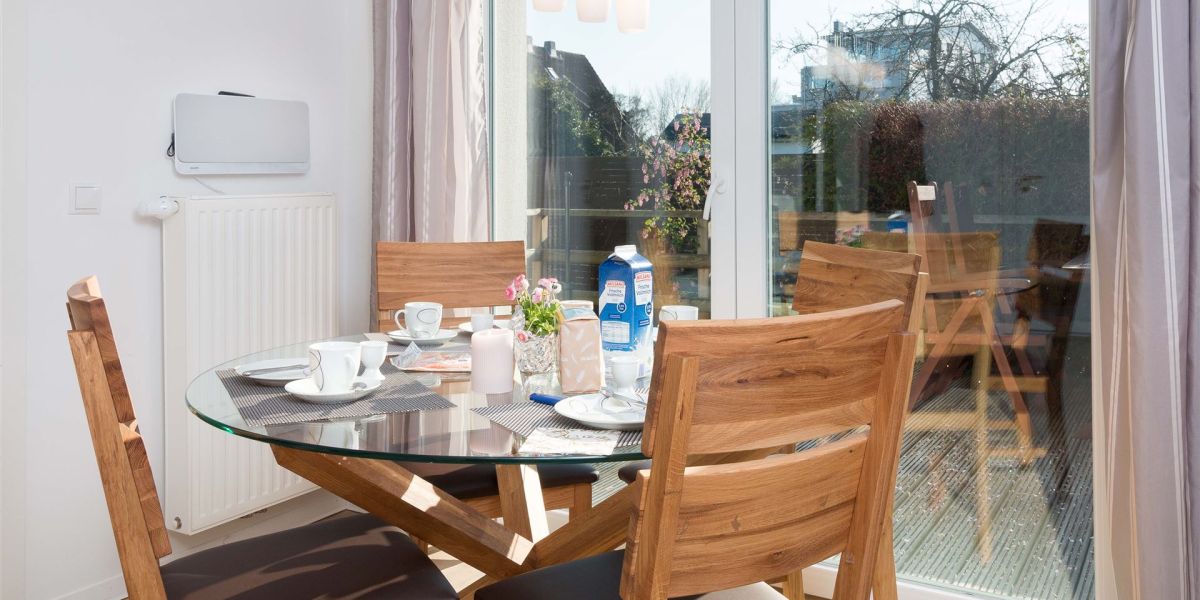 Essplatz mit vier Holzstühlen an der großen Fensterfront des Strandhaus-Bungalows K2