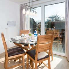 Essplatz mit rundem Glastisch und vier Holzstühlen im Strandhaus-Bungalow K2